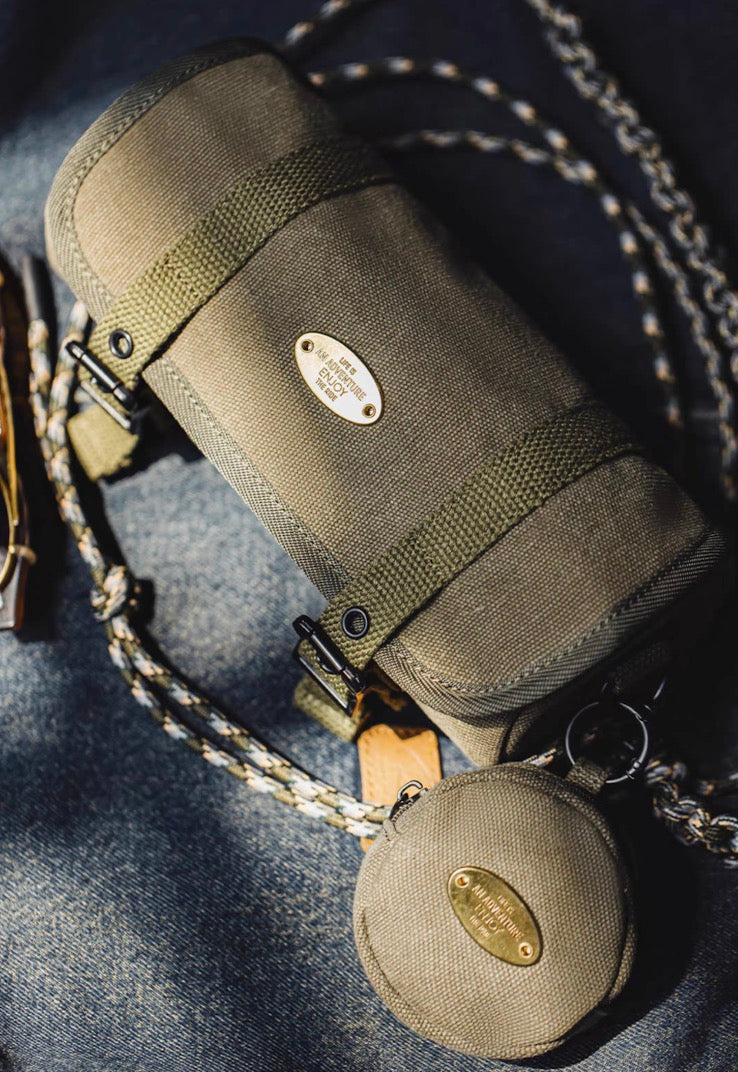 Olive canvas tool roll crossbody bag and coin pouch displayed on denim fabric