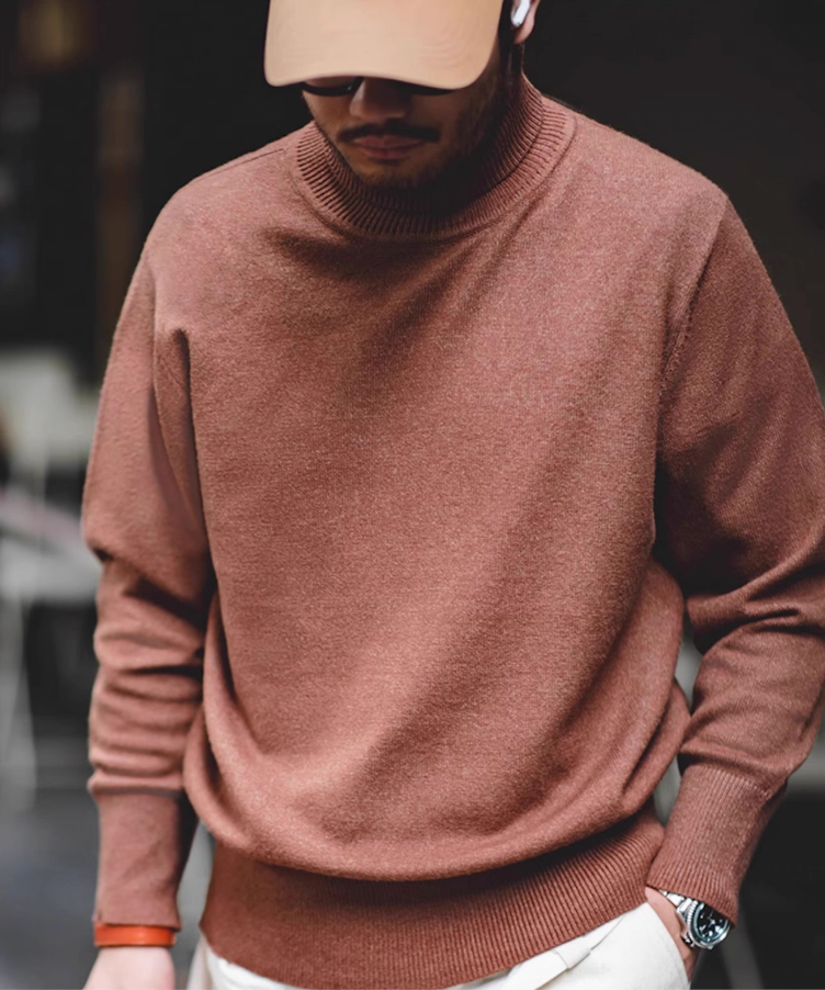 Man wearing mocha brown turtleneck sweater with beige pants in soft indoor light