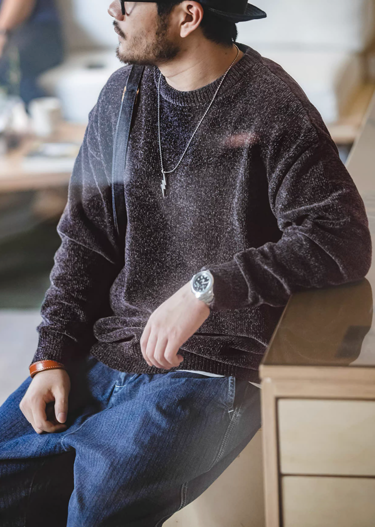 Model seated wearing dark purple chenille sweater with jeans in a cozy café setting