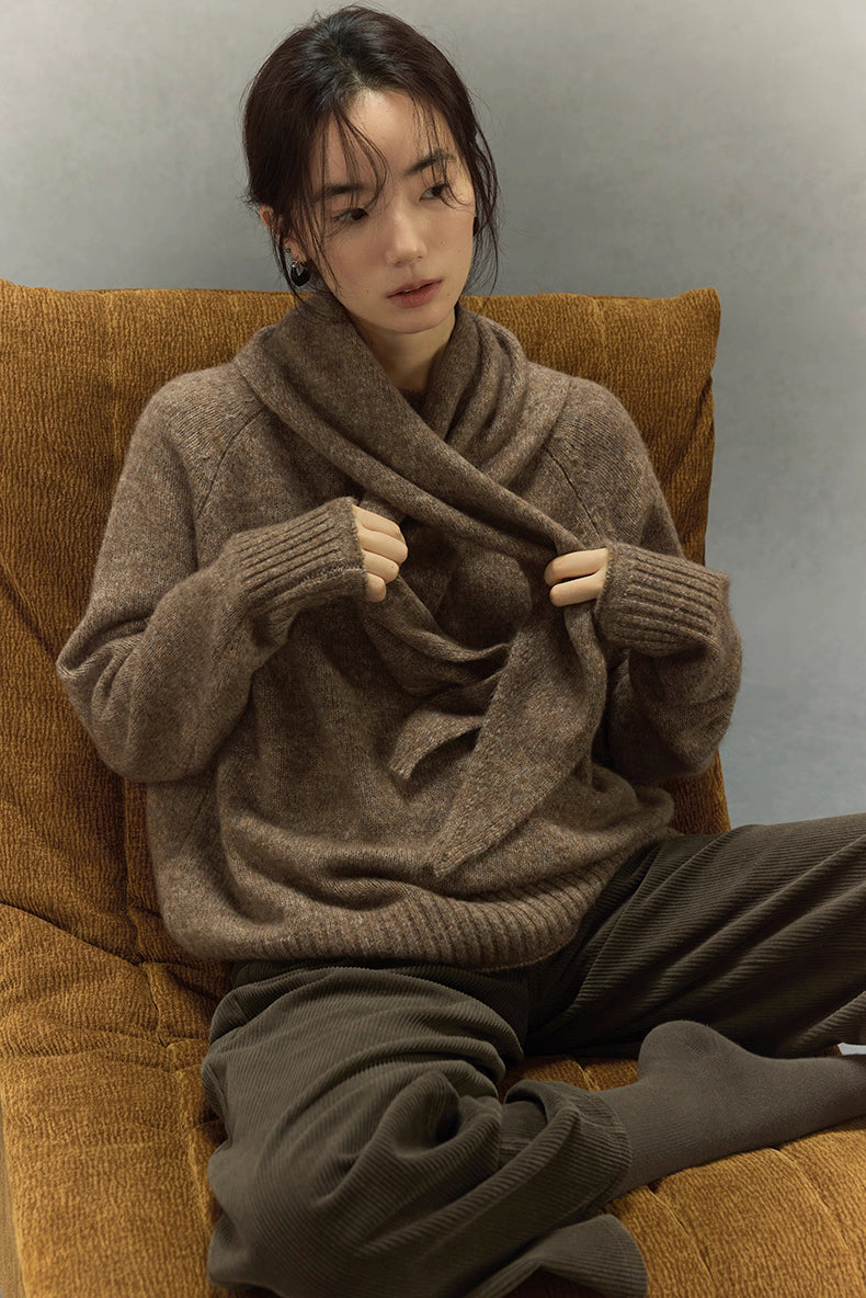 Woman sitting in light brown cashmere wool sweater, paired with matching scarf sold separately.