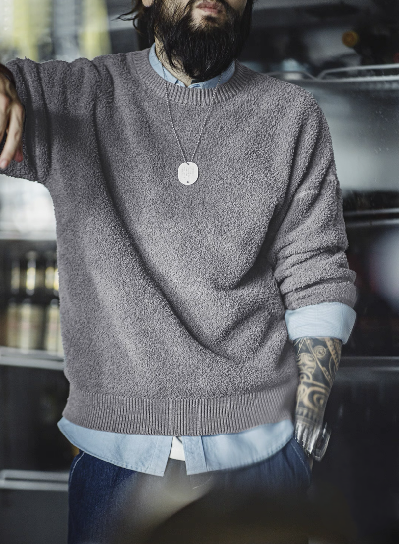 Man in light grey textured sweater styled with denim and shirt underneath