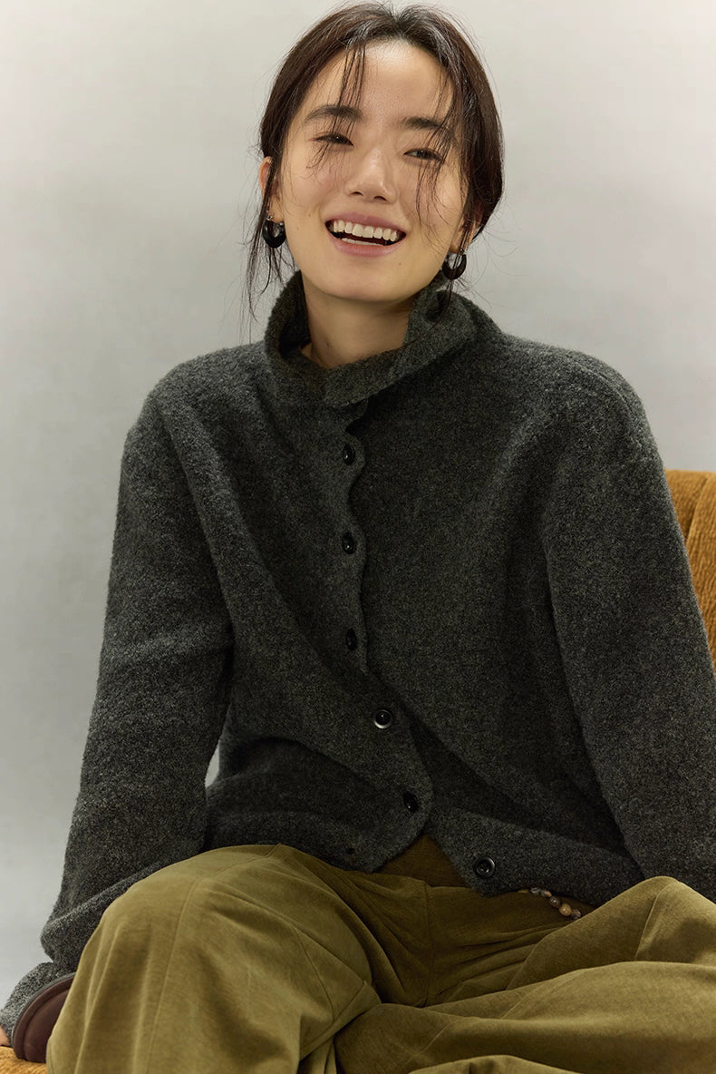 Close-up of model seated and laughing in cozy dark charcoal wool cardigan, highlighting plush texture and natural drape.
