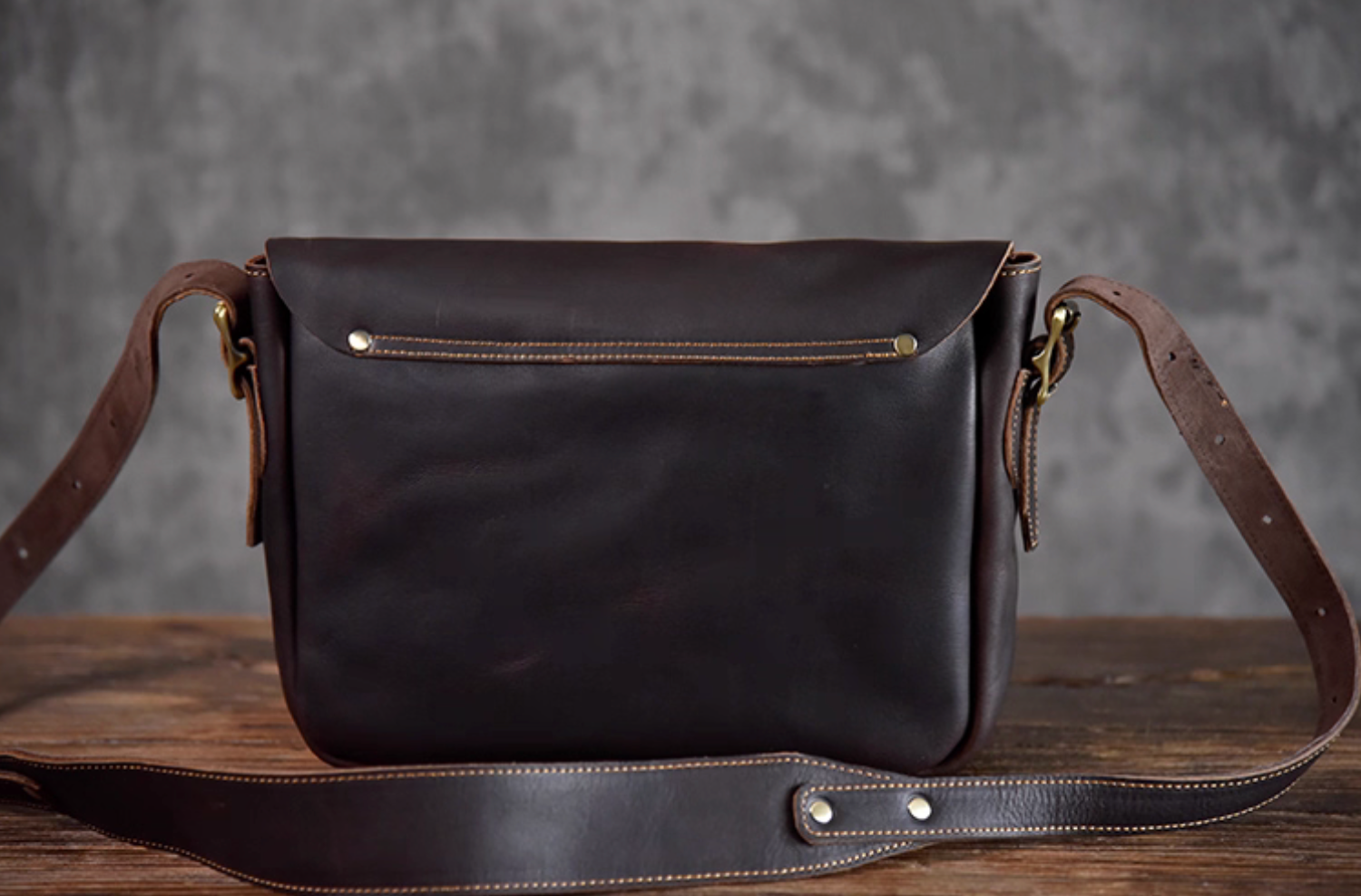 Back view of the dark chocolate leather messenger bag with rear slip pocket and adjustable strap.