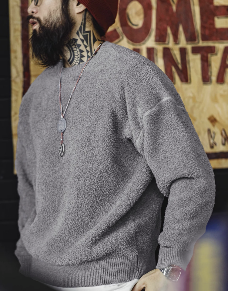 Man wearing light grey fleece sweater and red beanie in urban vintage setting