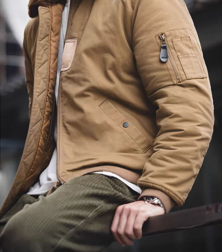 Man sitting outdoors wearing khaki B-15 flight jacket styled with corduroy pants