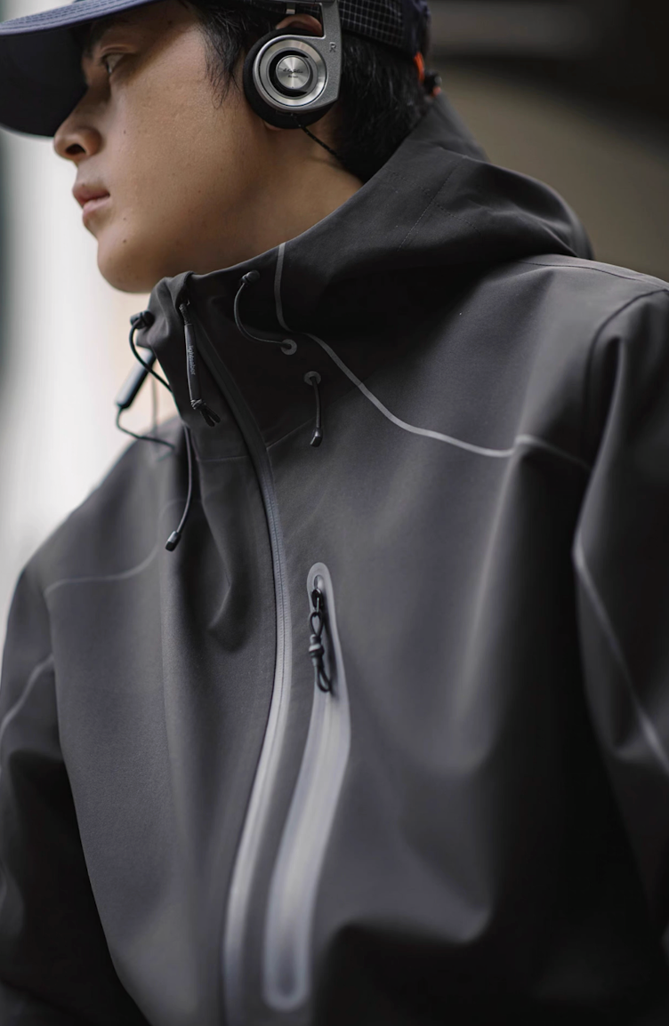 Side profile of model wearing grey LIGHTSABER Reflective Waterproof Tech Jacket