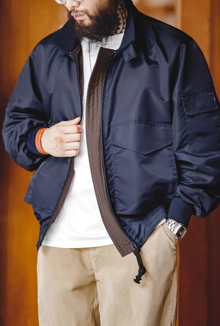 Man wearing G-8 Navy Flight Jacket indoors with tan pants and white tee, partially unzipped.