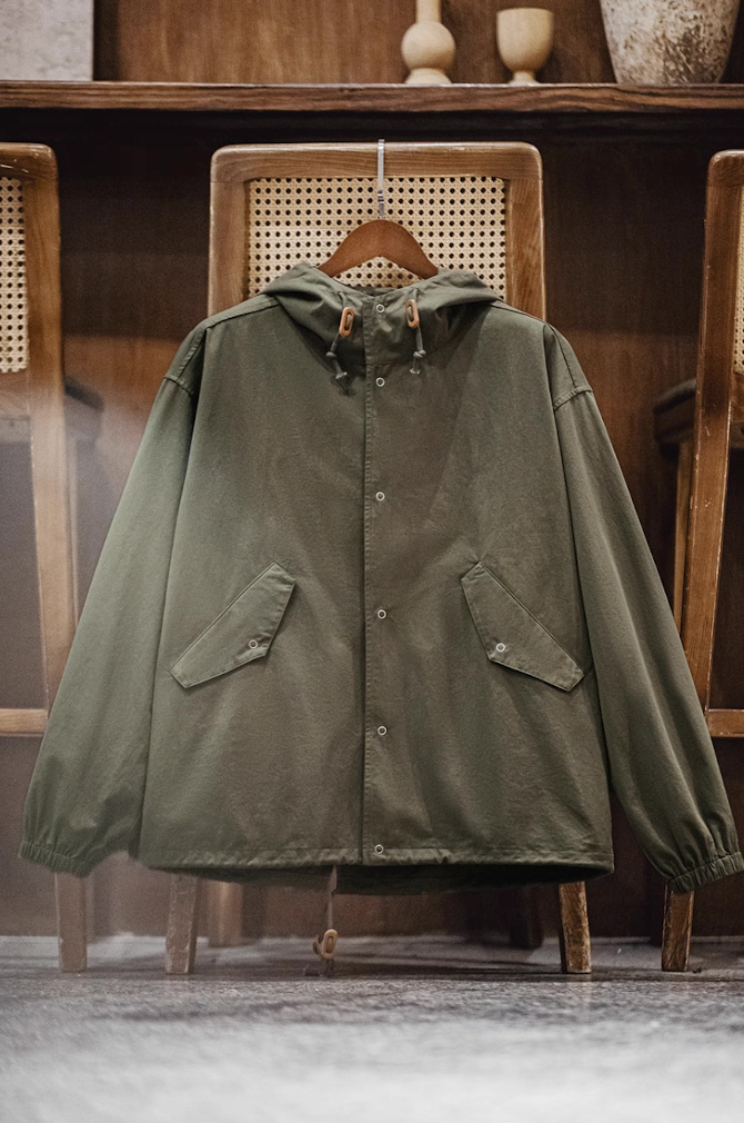 Army green cotton M-51 hooded jacket hanging in interior setting