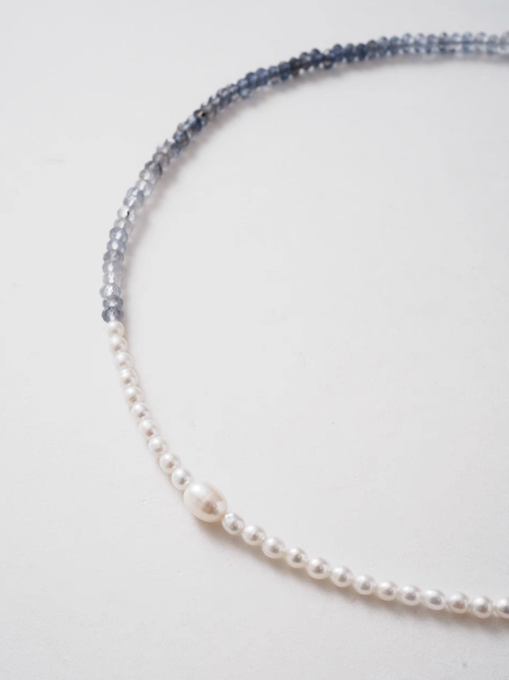 Close-up detail of harmony pearl and gem necklace highlighting transition between freshwater pearls and blue gray natural stone beads with central pearl
