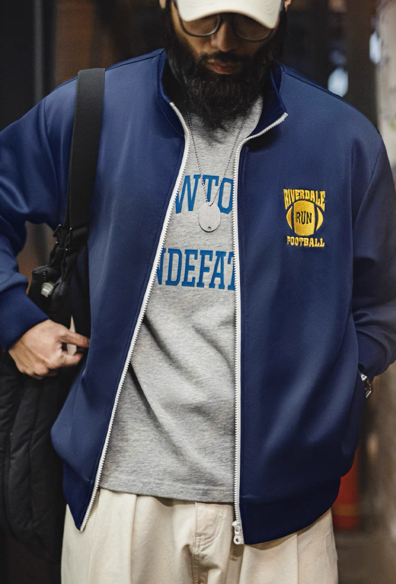 Model wearing Riverdale Run jacket open over gray tee in urban setting