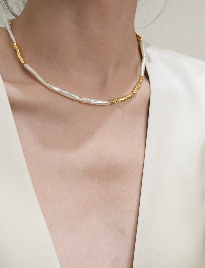 Close-up of baroque pearl gold accent choker necklace on model with blazer highlighting gold accent and pearl arrangement