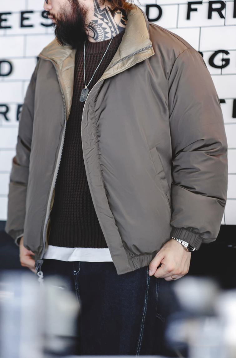 Model wearing grey side of Reversible Down Jacket indoors with coffee background