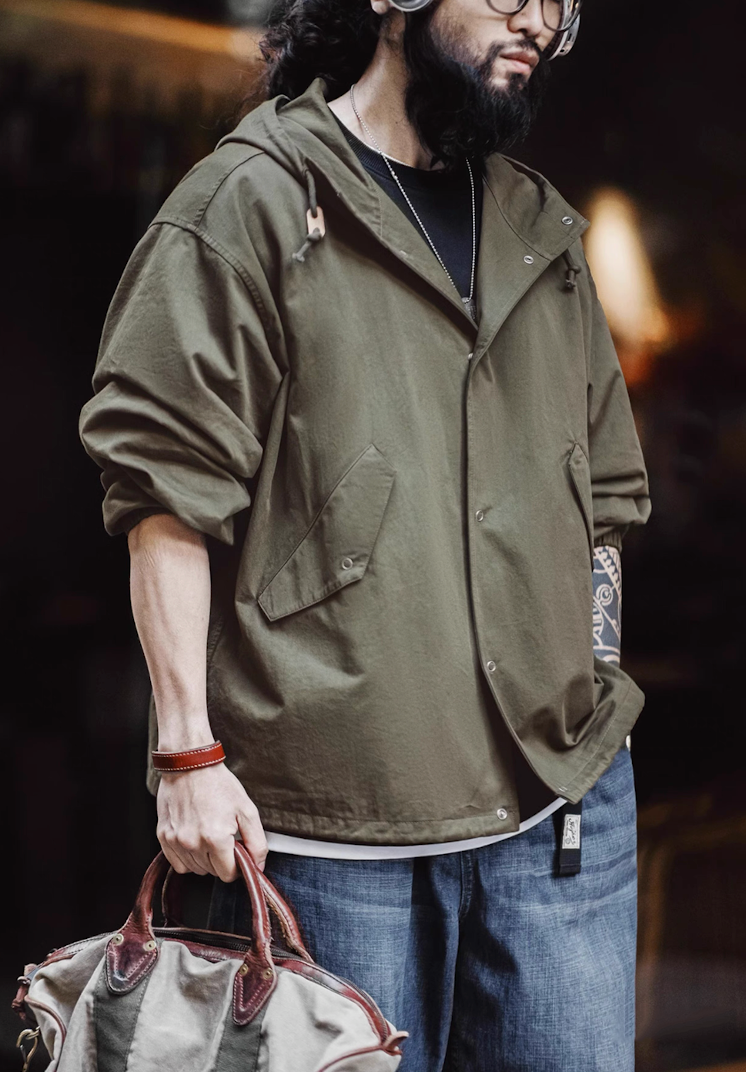 Model wearing army green cotton hooded jacket carrying canvas bag