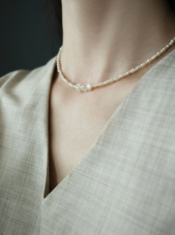 Close-up of baroque pearl and stone necklace on model highlighting natural freshwater pearls and subtle organic stone bead design