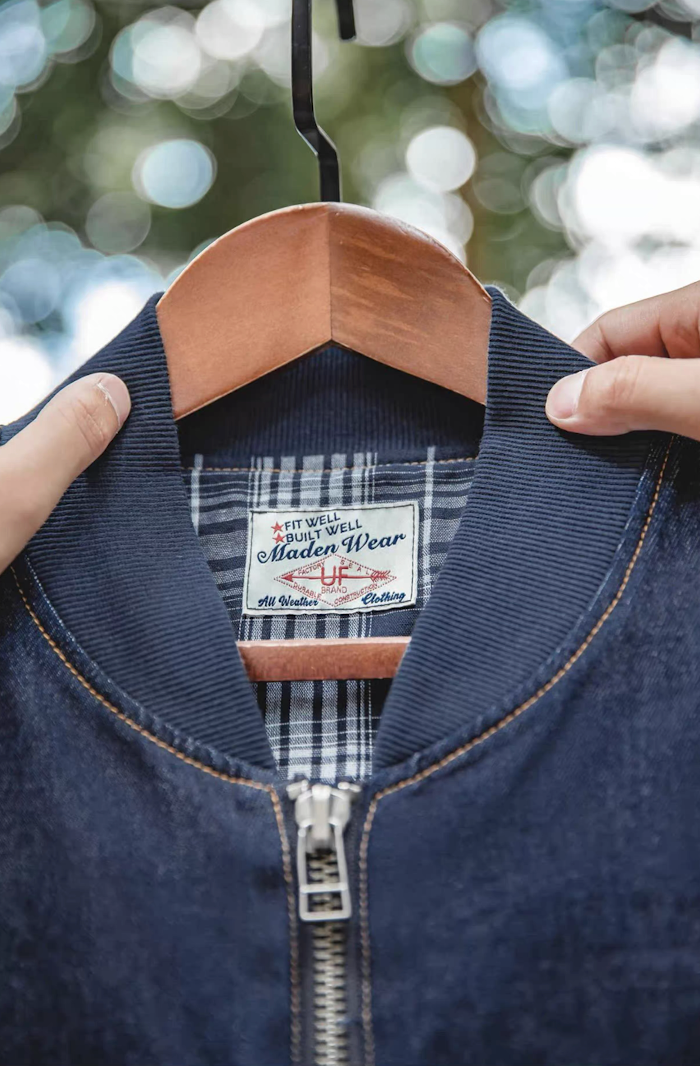 Close-up of ribbed collar and plaid inner lining on denim MA-1 jacket