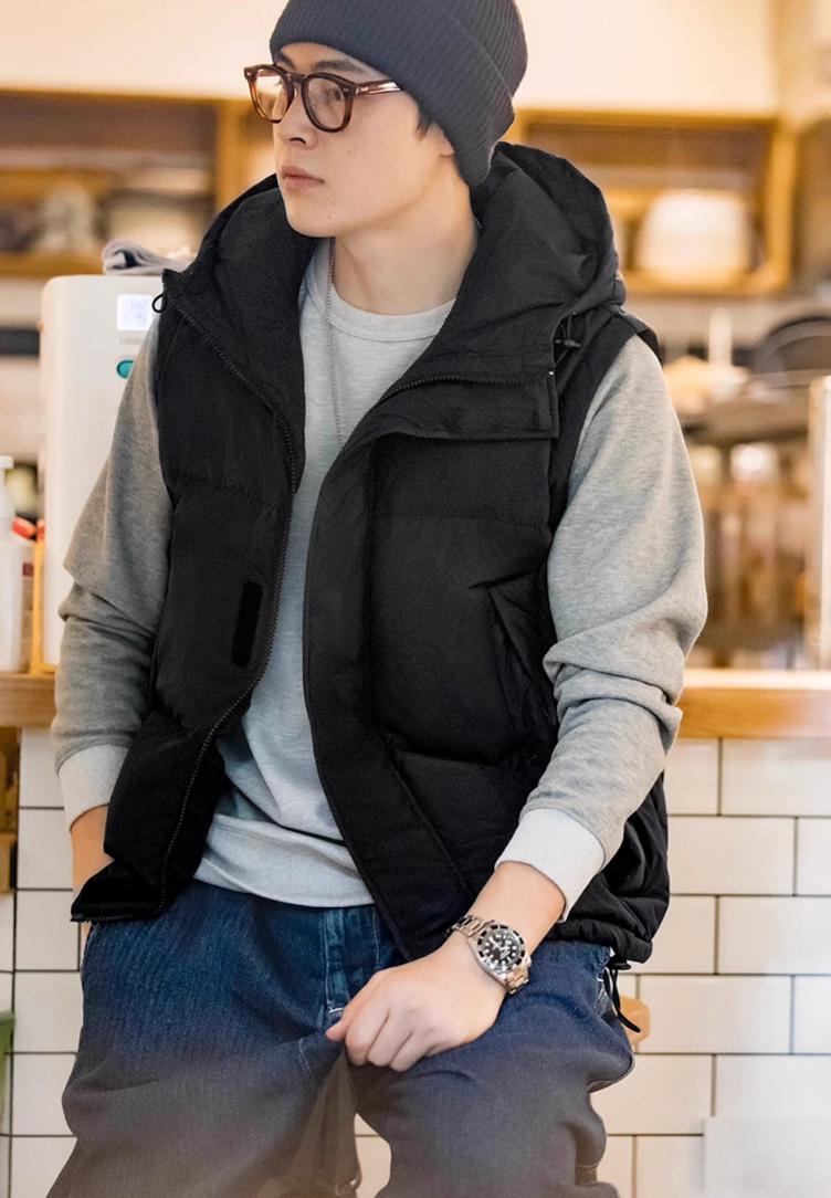 Model seated in black vest version of Versatile Parka with beanie