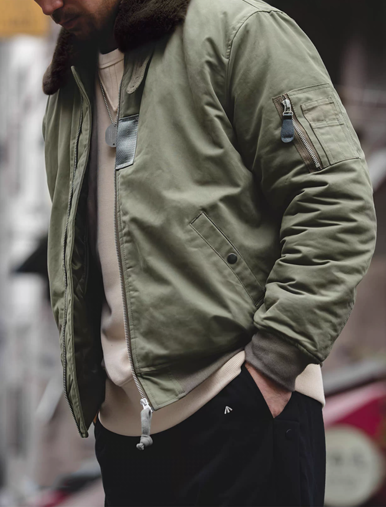 Side street view of green B-15 bomber jacket in casual outfit