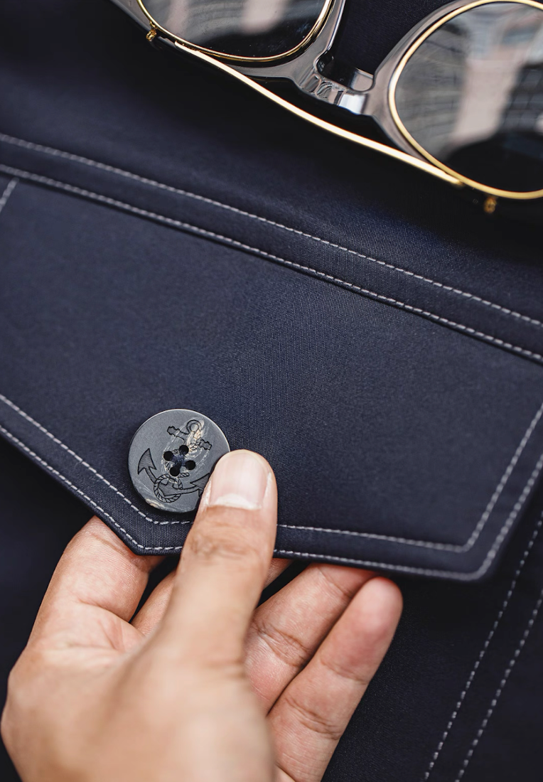 Anchor-engraved button detail on navy bomber jacket flap pocket