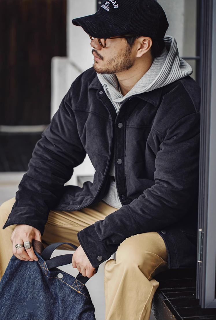 Man sitting in navy blue corduroy padded jacket with khaki pants