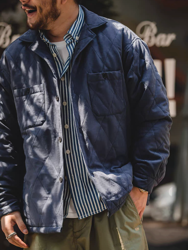 Man wearing navy blue quilted jacket over striped shirt