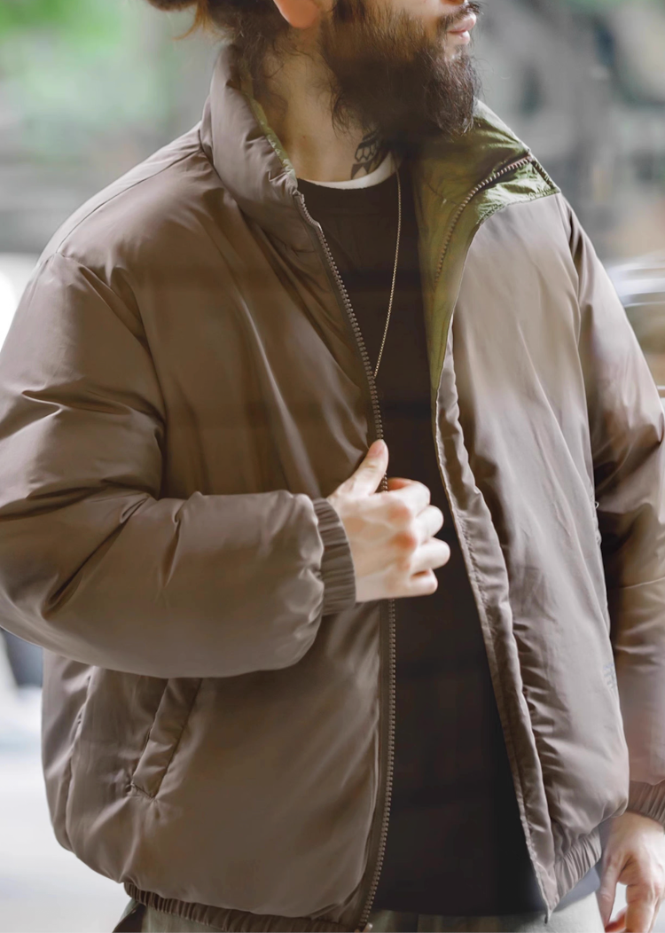 Model wearing grey inner side of Reversible Down Jacket with visible green lining