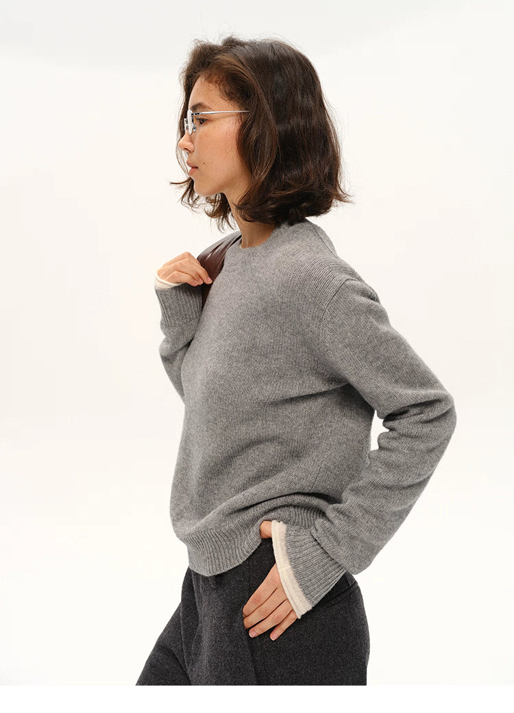Side profile of gray cashmere-blend sweater with model’s hand in pocket.