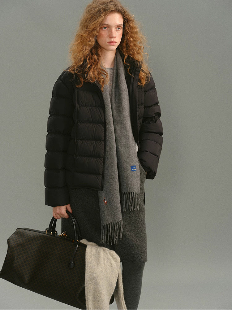 Full-body view of model wearing a black matte down puffer holding a travel bag.