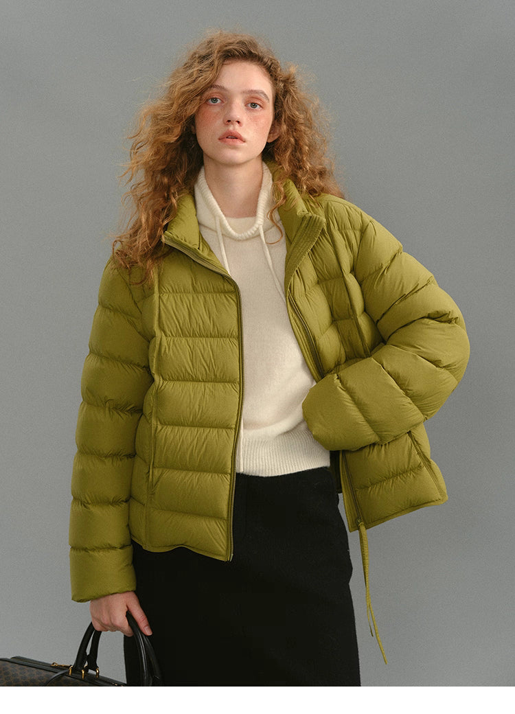 Model wearing a mustard green matte down puffer with a cream sweater.