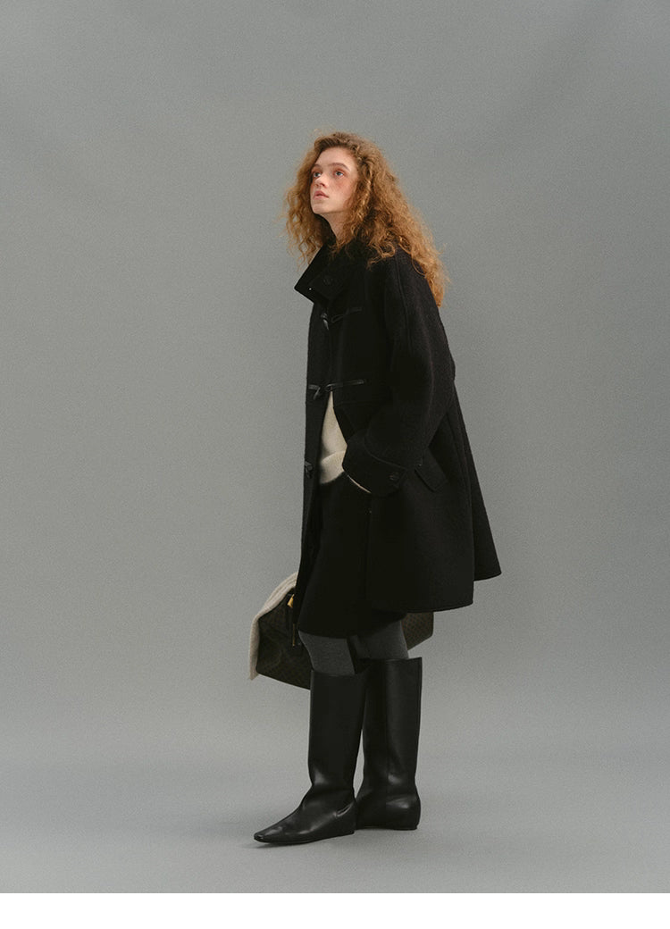 Full-height angle of black toggle coat with model looking upward.