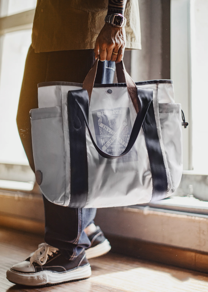 Lifestyle shot of model holding Ash Gray outdoor tote bag by window light