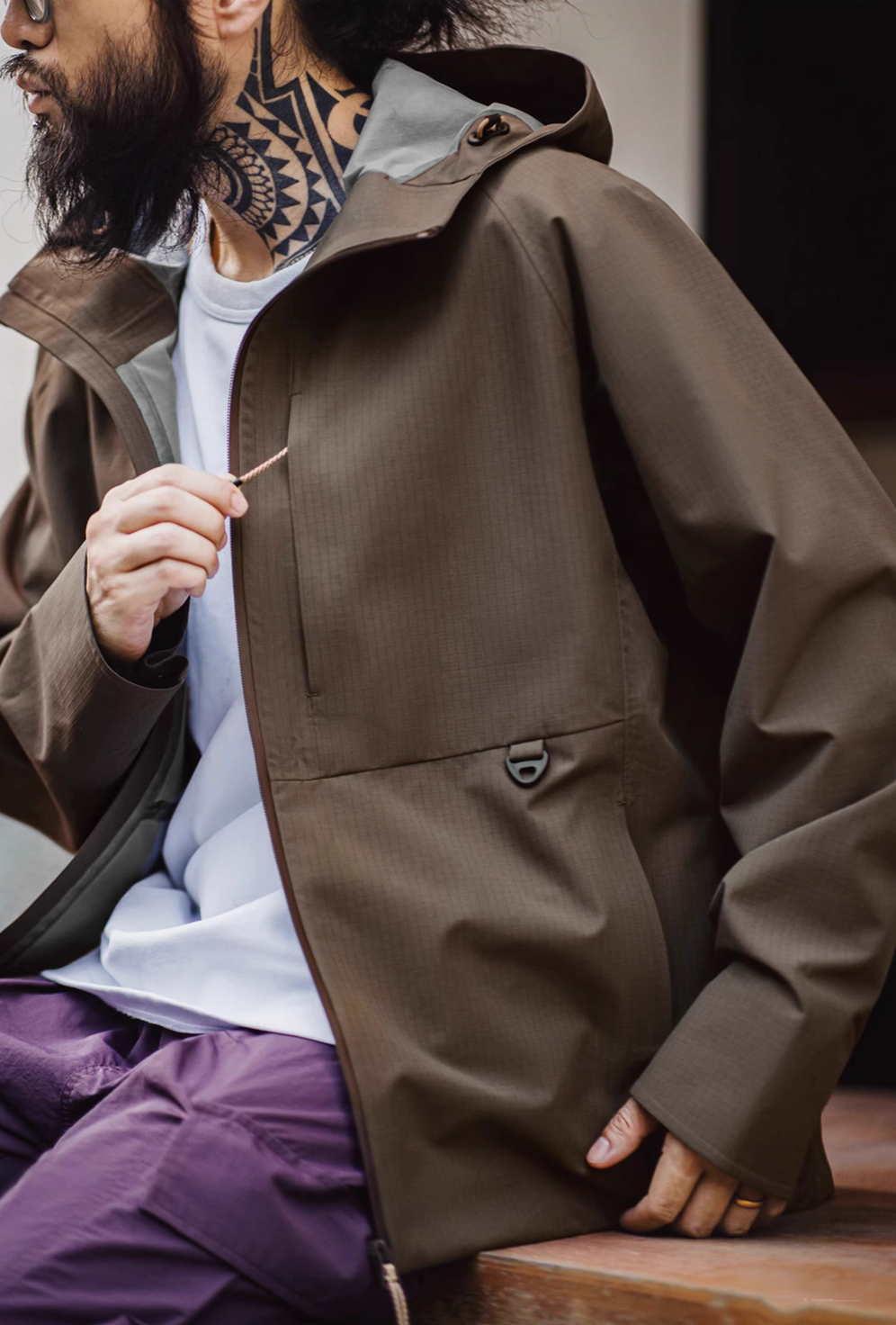 Khaki all-weather ripstop shell coat close-up front view highlighting textured fabric chest pocket and clean urban outdoor design