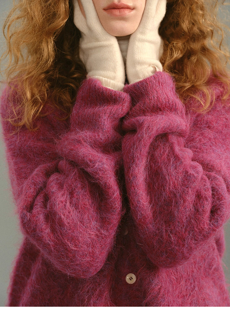 Close-up of Rose Plum alpaca cardigan with model warming hands against soft fuzzy sleeves