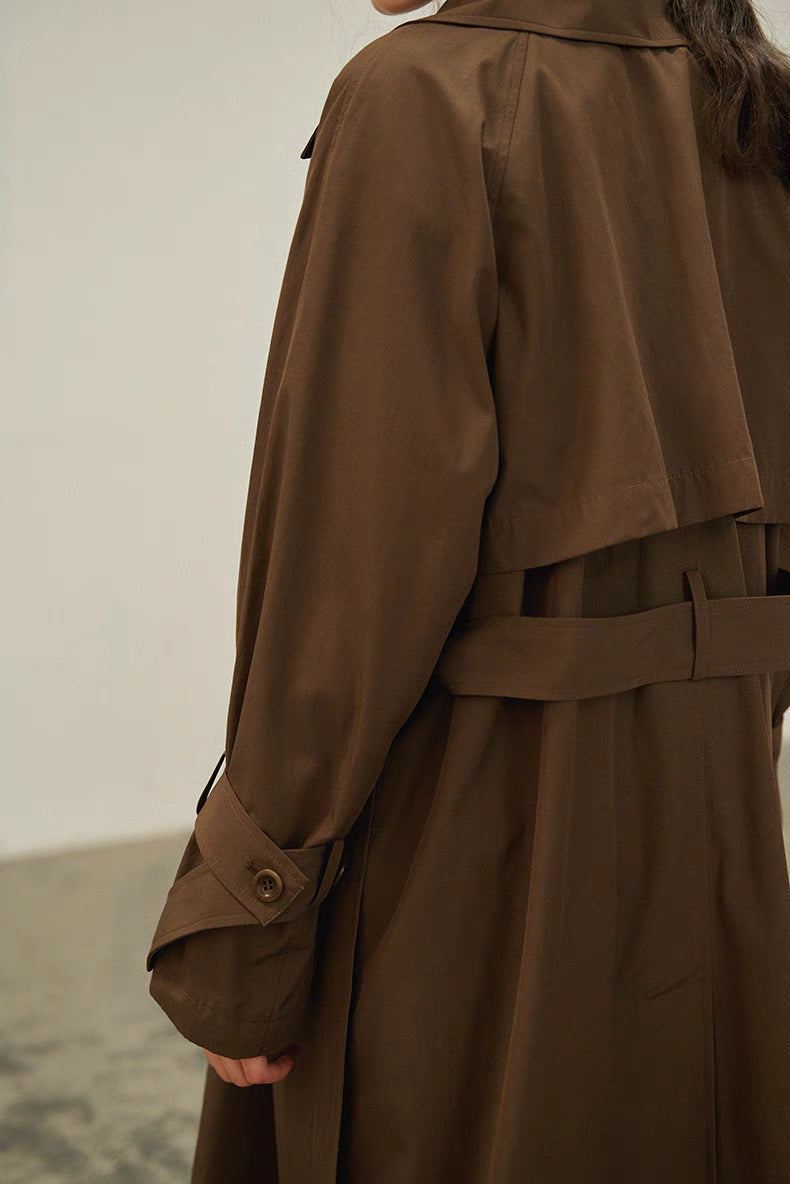 Dark brown trench coat back detail with storm flap, waist belt and clean tailored lines