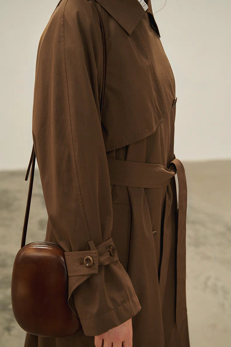 Dark brown trench coat side detail showing adjustable belt, sleeve cuff strap and soft drape