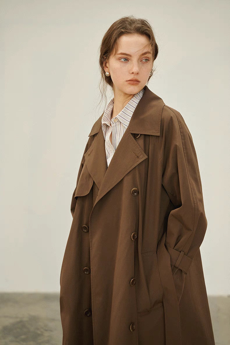 Dark brown trench coat three quarter front view showing spread collar and structured silhouette