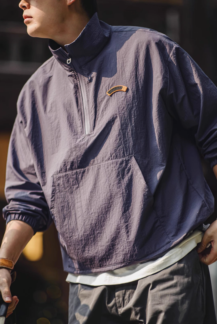 Model wearing dusty purple lightweight anorak jacket outdoors with half zip open