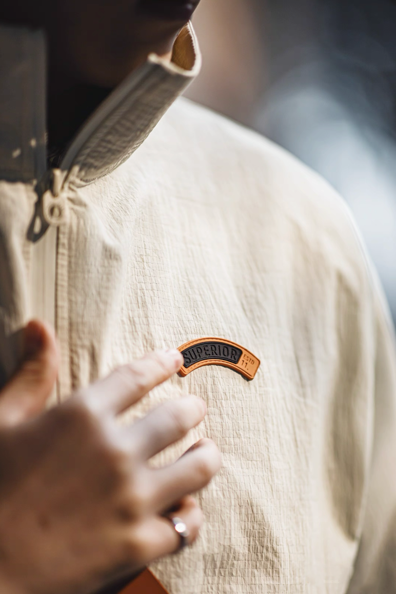 Close-up detail of off-white anorak jacket with Superior logo patch on chest