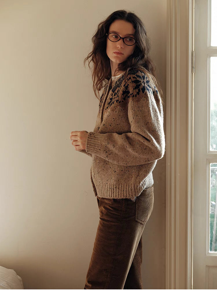 Khaki aran cable knit cardigan side profile view near window highlighting relaxed fit and textured wool knit