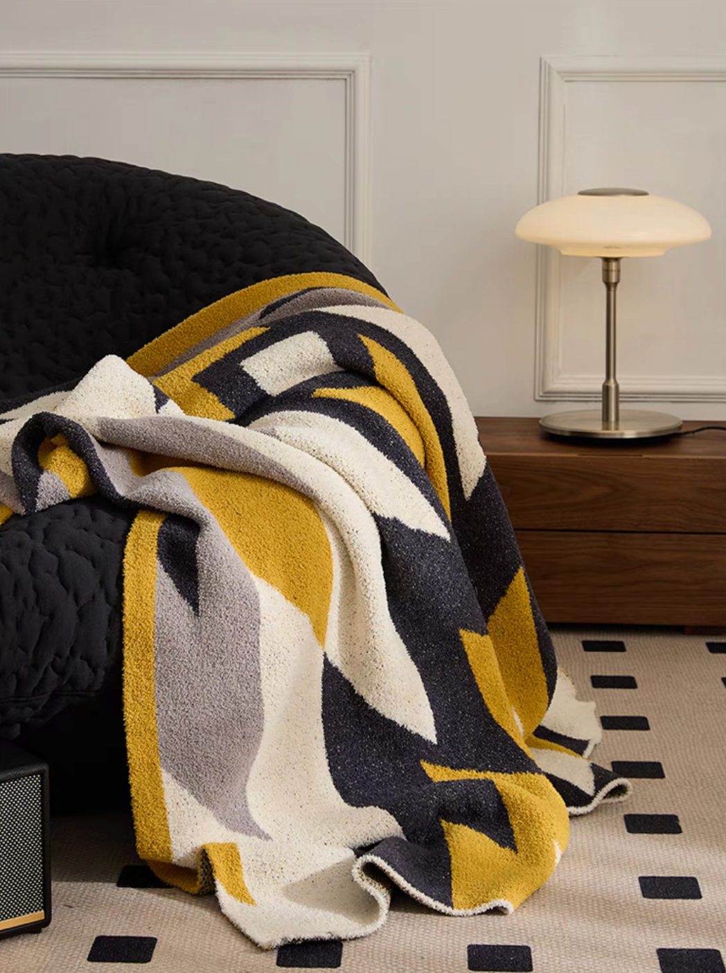 Dawn Ginger Yellow blanket draped over dark chair in modern interior highlighting geometric contrast design