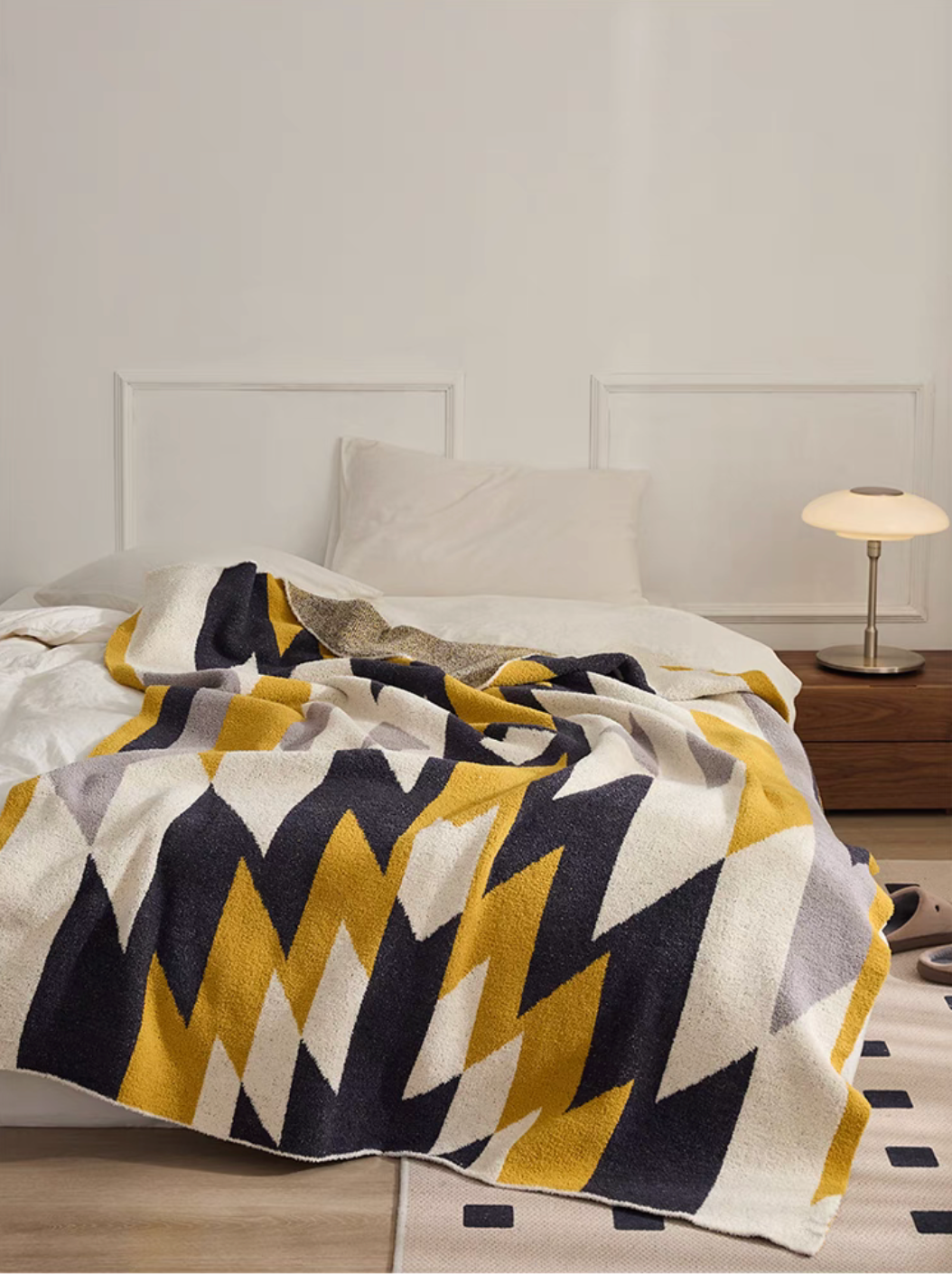 Angled view of Dawn Ginger Yellow blanket on bed showing natural folds and textured knit surface