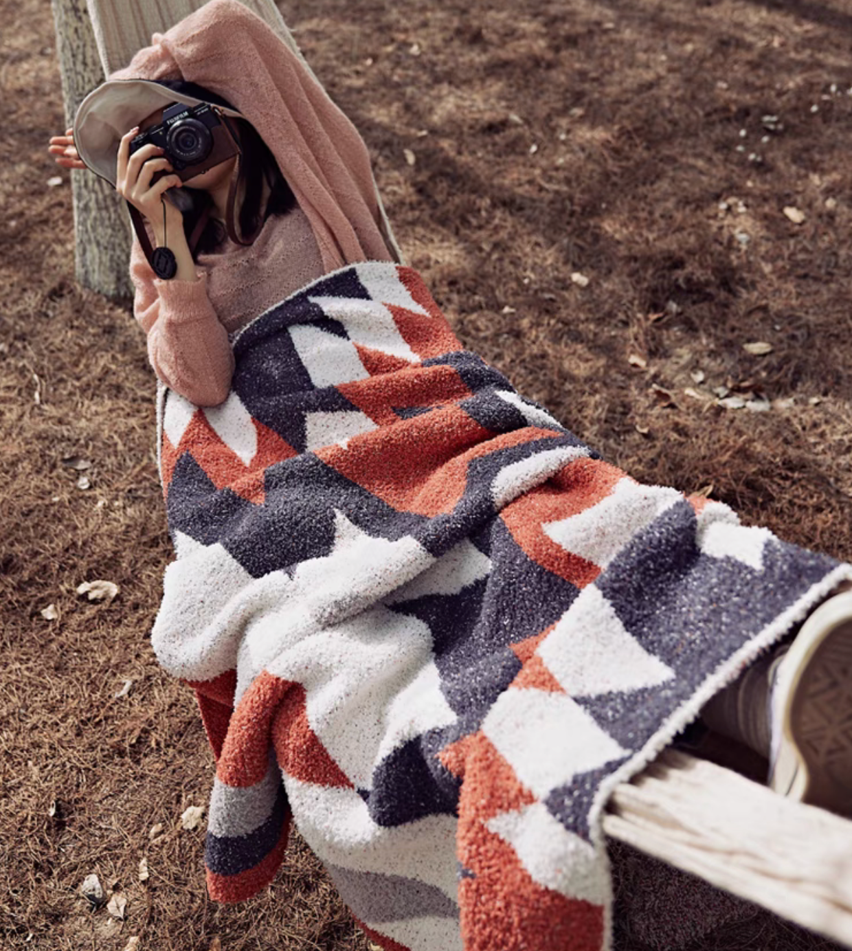 Person relaxing outdoors wrapped in Dawn Red blanket demonstrating portability and cozy outdoor use
