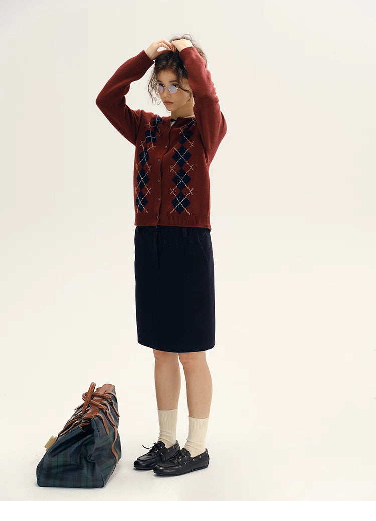 full body shot of model in wine red argyle cardigan with navy skirt