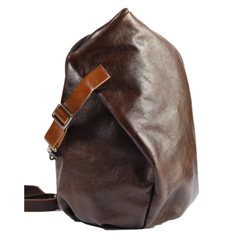 Dark brown leather sling bag standing upright on white background.