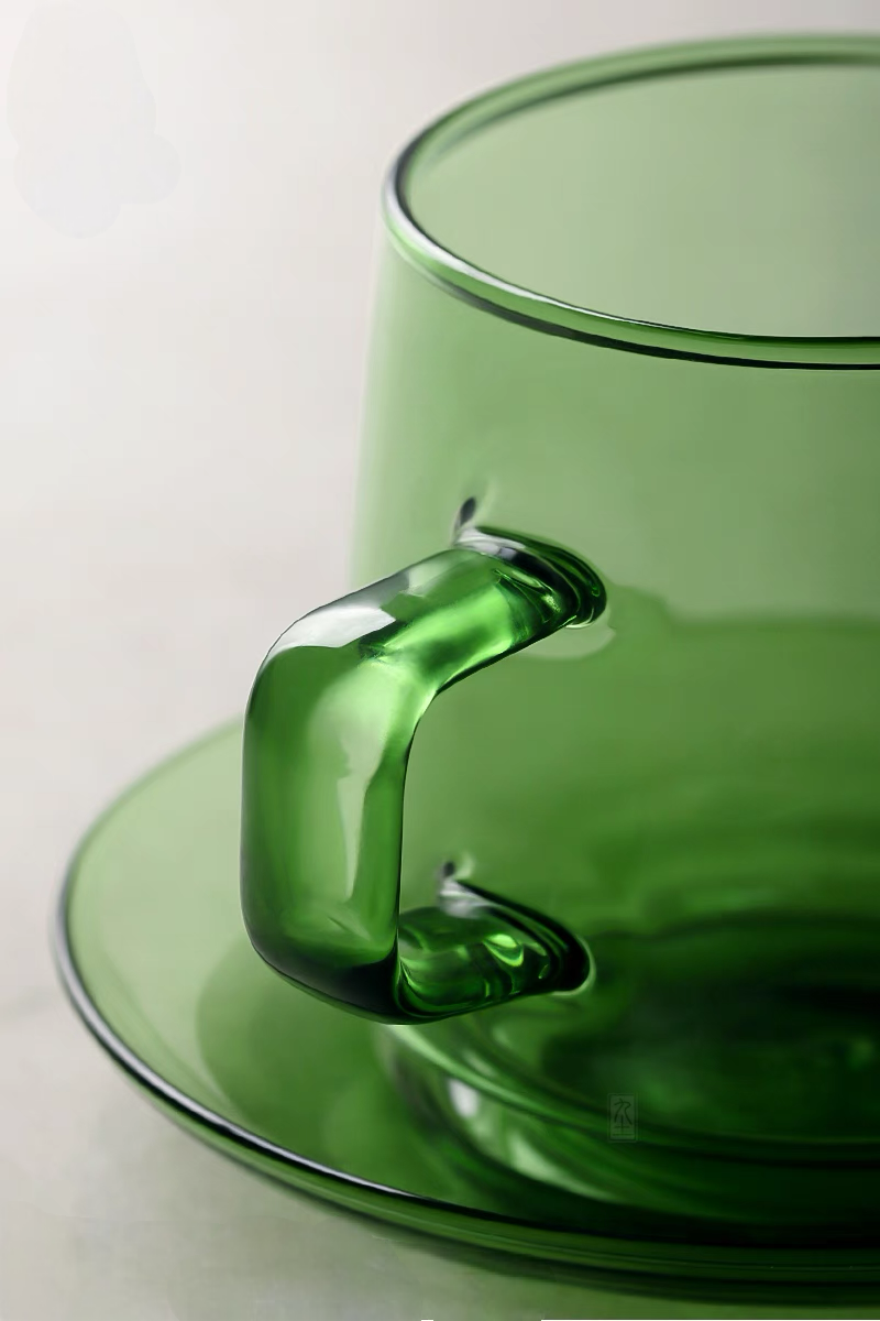 Close-up of green Aurora Harmony glass cup handle and saucer showing smooth borosilicate glass craftsmanship