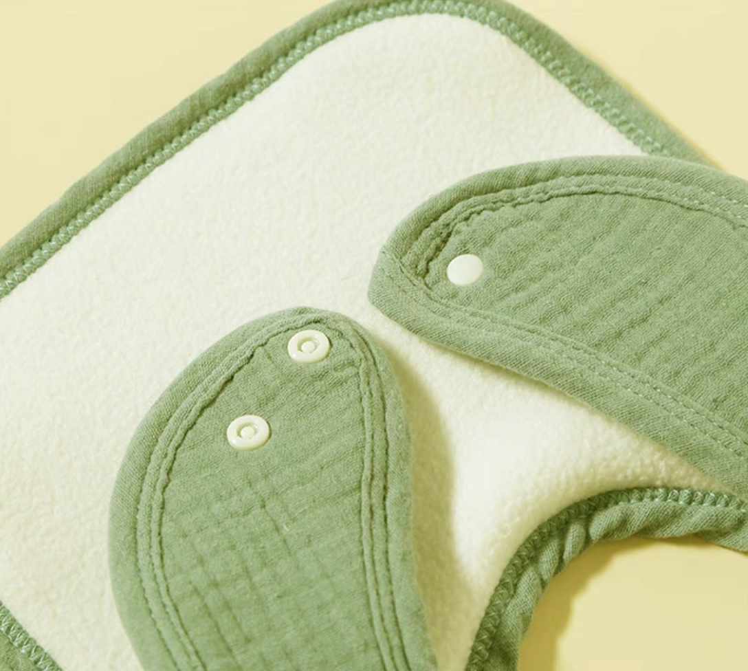 Green baby cotton gauze bib back side with soft fleece lining and snap closure detail