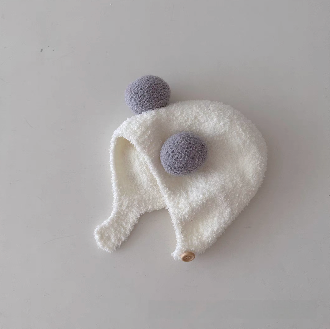 White baby pom pom hat with gray pom poms soft plush texture and warm ear coverage