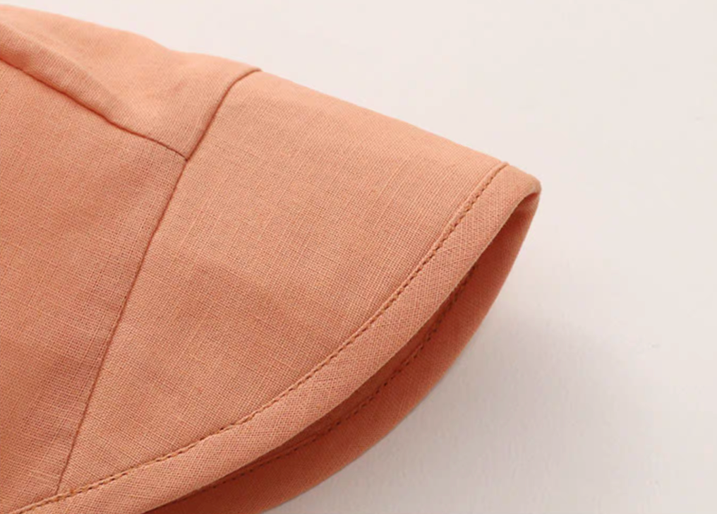 Close-up of orange baby sun hat brim showing fine stitching and linen cotton texture