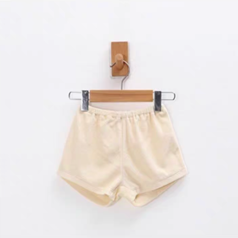 Cream baby terry cotton shorts with elastic waistband hanging on wooden hanger