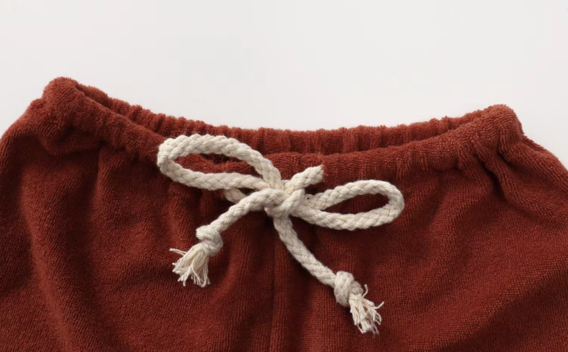 Close-up of rust red baby shorts waistband with adjustable drawstring detail
