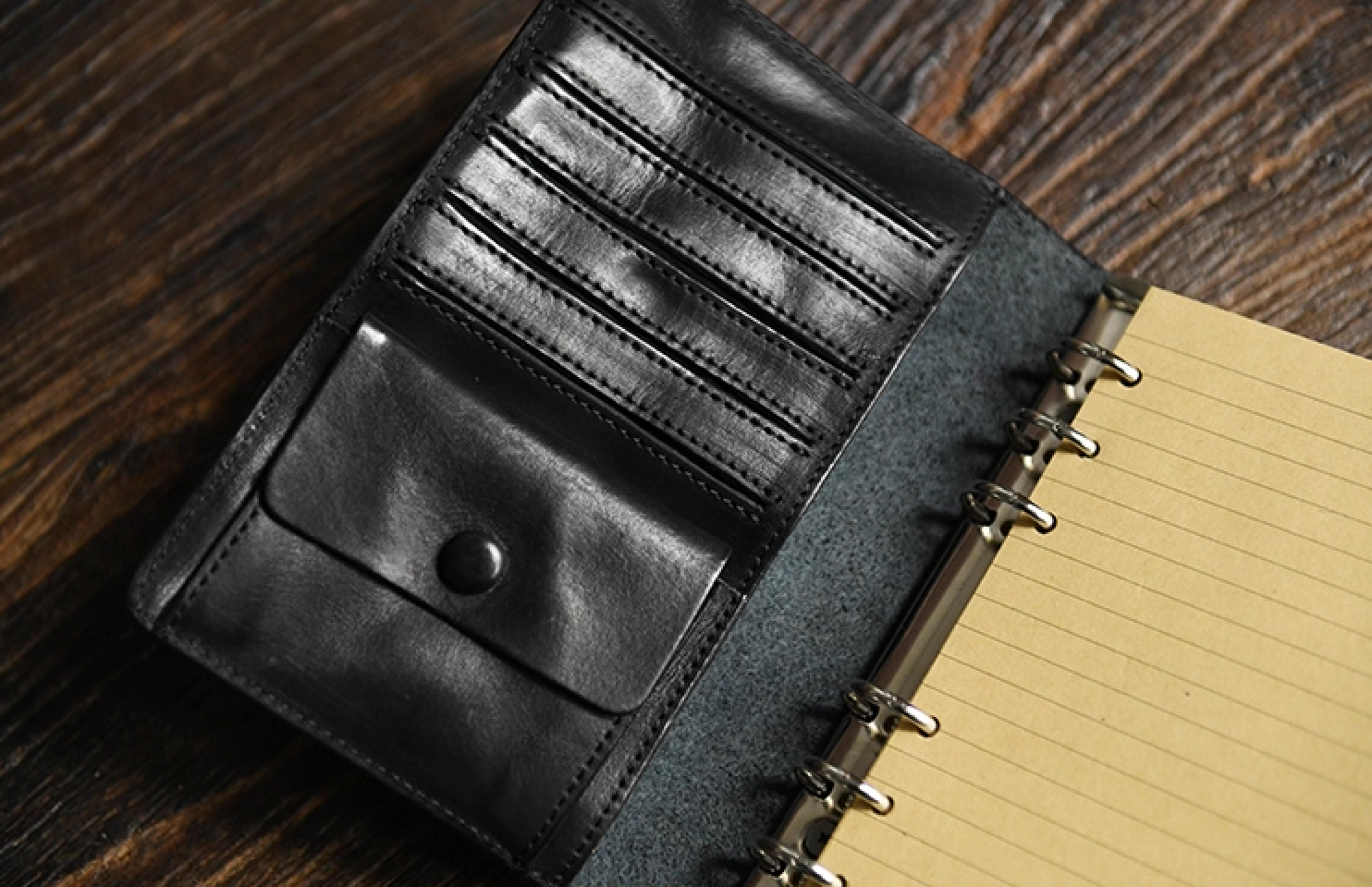 Open black leather refillable notebook displaying card slots and snap pocket interior.
